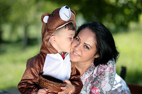 toddler in brown bear pramsuit kissing woman's cheek thumbnail