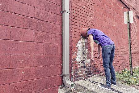 person wearing purple shirt and blue-washed jean inserting inside the wall thumbnail