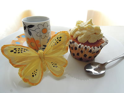cupcake, silver spoon, ceramic mug, and yellow butterfly decor on table thumbnail
