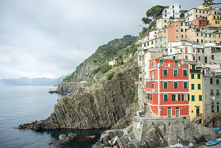 building on mountain beside body of water thumbnail