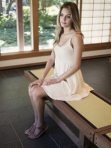 woman sitting on wooden bench near open door thumbnail