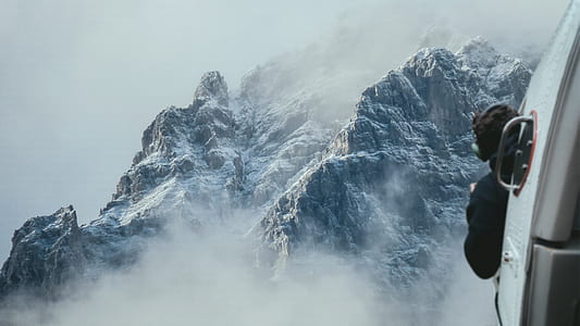 photo of man ride on helicopter near rock mountain covered with snow thumbnail