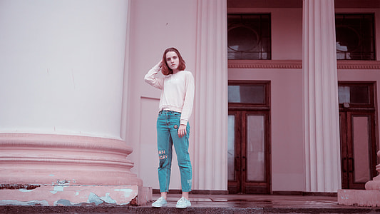 woman with white sweater and blue denim pants standing on white concrete building thumbnail