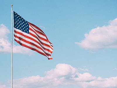 U.S. flag hoisted on gray metal pole under blue cloudy sky at daytime thumbnail