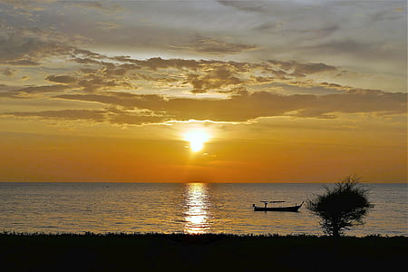 silhouette photography of boat on body of water during golden hour thumbnail