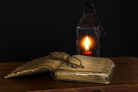 lighted candle near books and eyeglasses thumbnail
