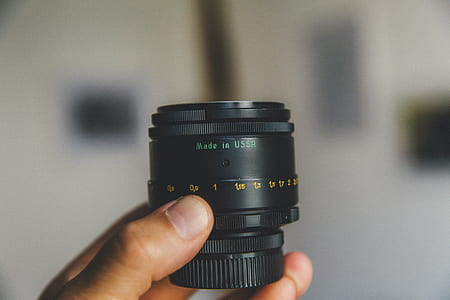 person holding black camera lens thumbnail