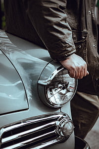 man wearing brown leather jacket leaning on gray car thumbnail