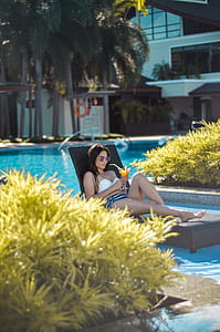 Woman Sitting on Outdoor Lounger Chair While Holding Drinking Glass thumbnail
