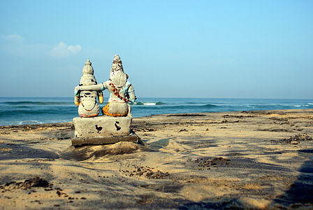 two deity statuette on seashore at daytime thumbnail