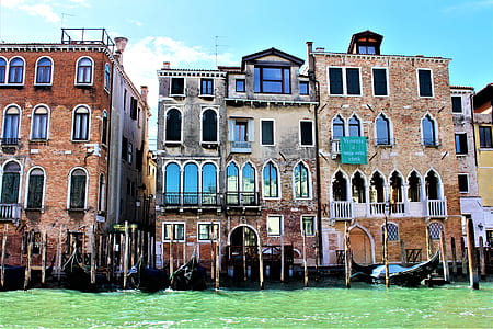 selective focus photography of mid rise building near body of water under white clouds and blue sky thumbnail
