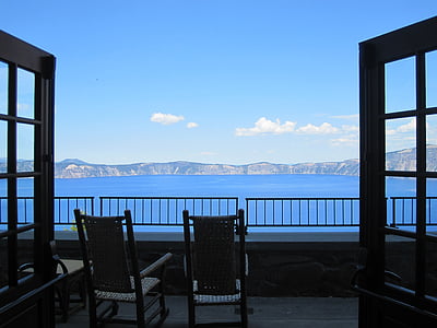 silhouette photography of two armchairs in front of body of water under blue sky thumbnail