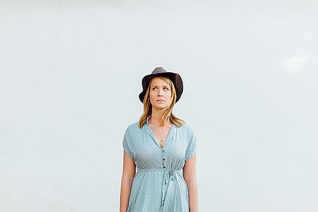 woman wearing hat and blue dress with eyes looking up thumbnail