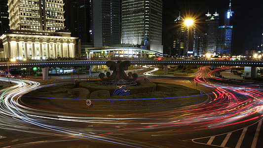 timelapse photography of red and white lights crossing on road near building at nighttime thumbnail