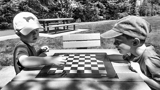 grayscale photo of two boys playing chess thumbnail