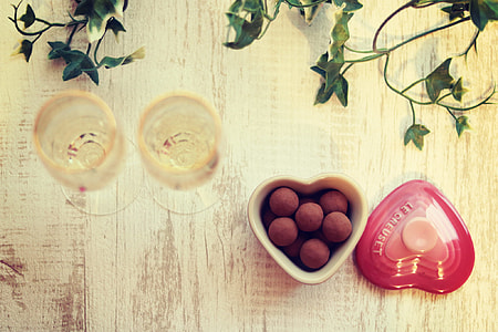 two clear long-stem wine glass beside heart-shaped ceramic container filled with pastries thumbnail