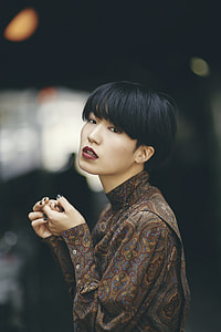 selective focus photo of woman wearing brown, gray, and red paisley long-sleeved shirt thumbnail
