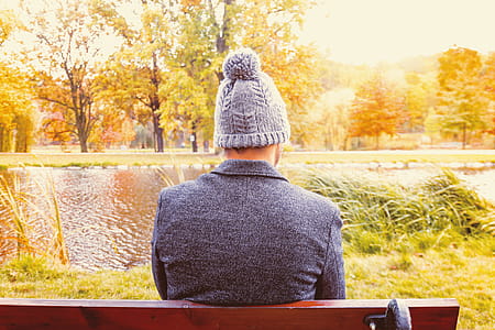 A young man sitting on a bench at the park in autumn thumbnail