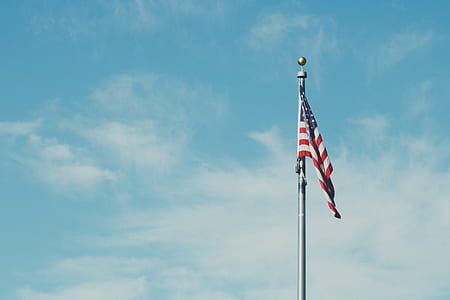 flag of America on gray pole with clouds thumbnail