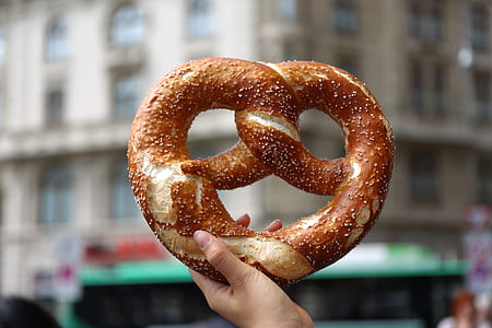 shallow focus photography of person holding pretzel thumbnail
