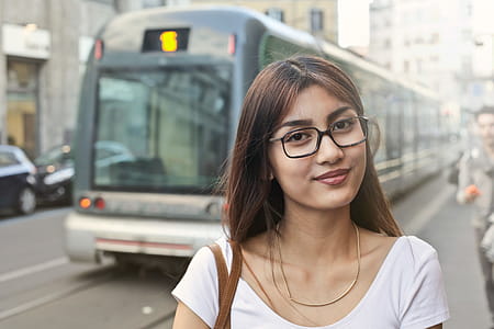 Young Asian Woman In White T-Shirt And Spectacles Standing Near Running Tram On The Road thumbnail