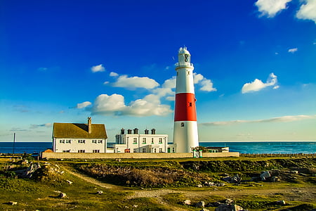 white and red lighthouse beside body of water under blue and white sky at daytime thumbnail