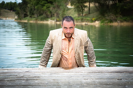 man in beige notched lapel suit on body of water thumbnail
