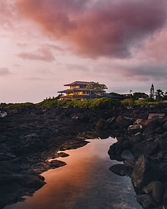 landscape photography of body of water and house near cliff thumbnail