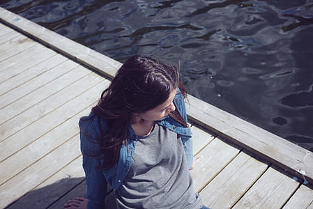 woman wearing blue denim jacket on gray wooden sea dock thumbnail