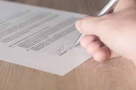person holding pen while signing in printing paper thumbnail