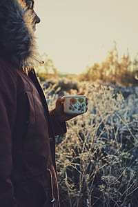 person holding white and orange floral mug thumbnail