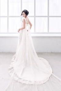 woman wearing white sleeveless bridal gown near window during daytime thumbnail