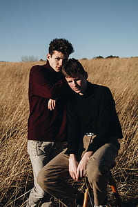 man leaning on another man in the middle of grassfield during day thumbnail