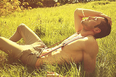 man in gray fitted jean with red suspender lying on grass field during daytime thumbnail