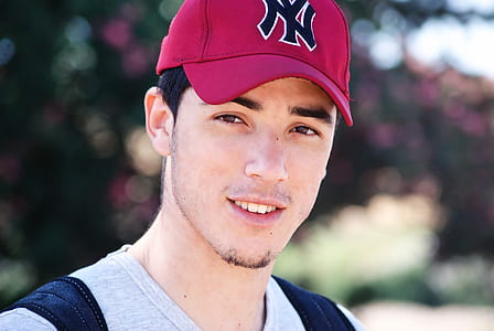 selective focus photography of smiling man wearing red New York Yankees fitted cap thumbnail