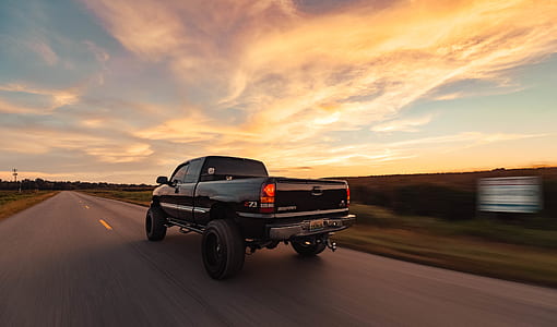 black pickup truck on road unde white and blue sky thumbnail