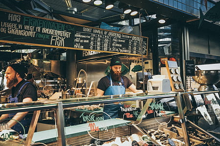 man with blue apron stands near glass display counter thumbnail