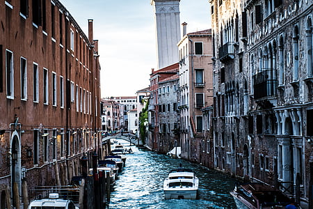 white motor boat in between concrete houses thumbnail