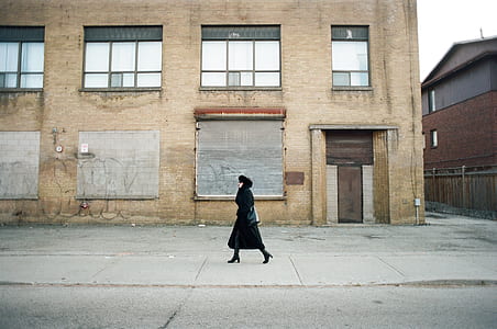 woman walking on sidewalk beside closed roller shutter thumbnail