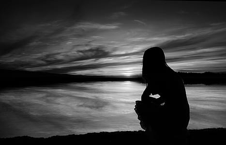 silhouette of woman sitting near water thumbnail