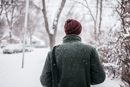 man black green coat standing near trees covered by snow with vehicle ahead during winter thumbnail