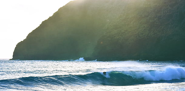 person riding on surfboard near mountain thumbnail
