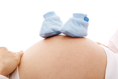 baby's pair of teal socks on women's stomach thumbnail