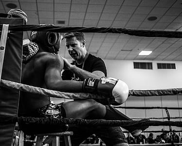 coach talking to boxer on ring's corner in grayscale photography thumbnail