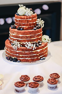 brown icing covered 3-tier cake with cupcakes thumbnail