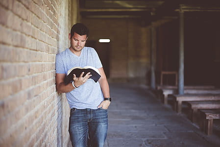 man leaning on wall reading book thumbnail