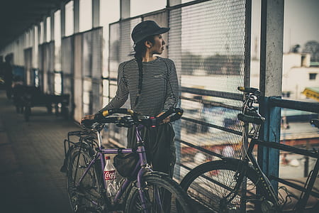 woman holding bicycle near rails thumbnail