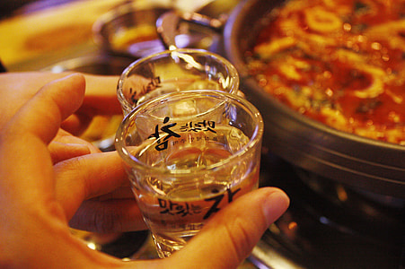 person holding clear shot glass thumbnail