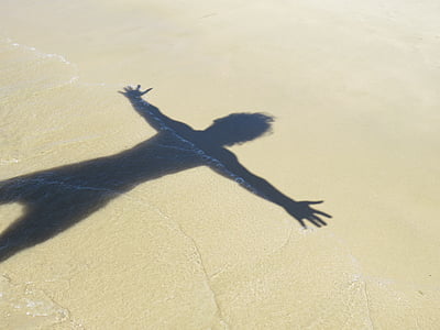 human shadow on beach sand during daytime thumbnail