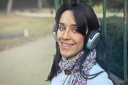 Young Woman Wearing Scarf While Using Headphones To Listen To The Music In The Park thumbnail